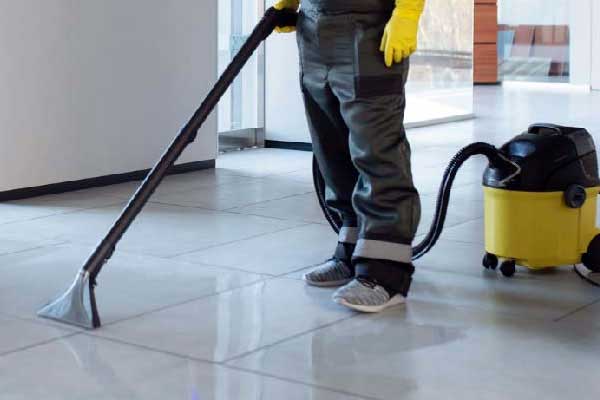 Janitor using industrial vacuum cleaner on shiny commercial floor representing heavy duty cleaning supplies