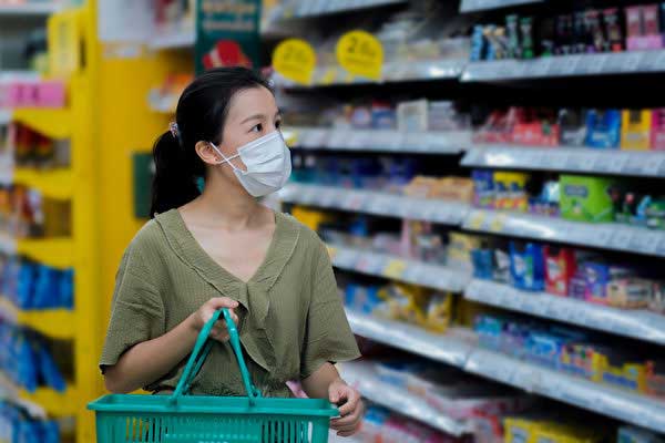 Customer with a shopping basket in a grocery store aisle looking for retail ready wet wipes