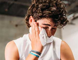 A man wiping sweat with a cooling wipe after a gym workout or sports training