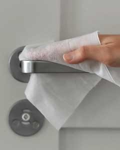 Wiping and sanitizing a high-touch metal door handle with a professional surface disinfection wet wipe to prevent germ spread.