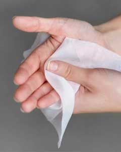 A person cleaning their hands with a portable sanitizing wet wipe for immediate hygiene care in professional workplaces.